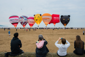 People photographing and filming hot air balloons on a beach, representing Exclusive Ballooning’s expertise in hot air balloon marketing campaigns.